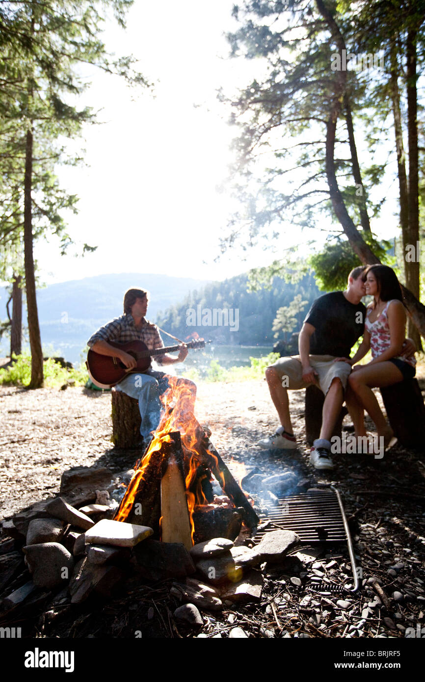 I giovani adulti camping sedersi attorno a un fuoco accanto a un lago in Idaho. Foto Stock