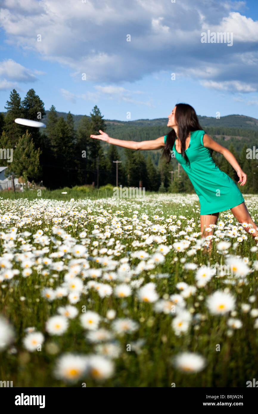 Una giovane e bella donna sorrisi mentre threwing un frisbee in un campo di  fiori selvatici Foto stock - Alamy