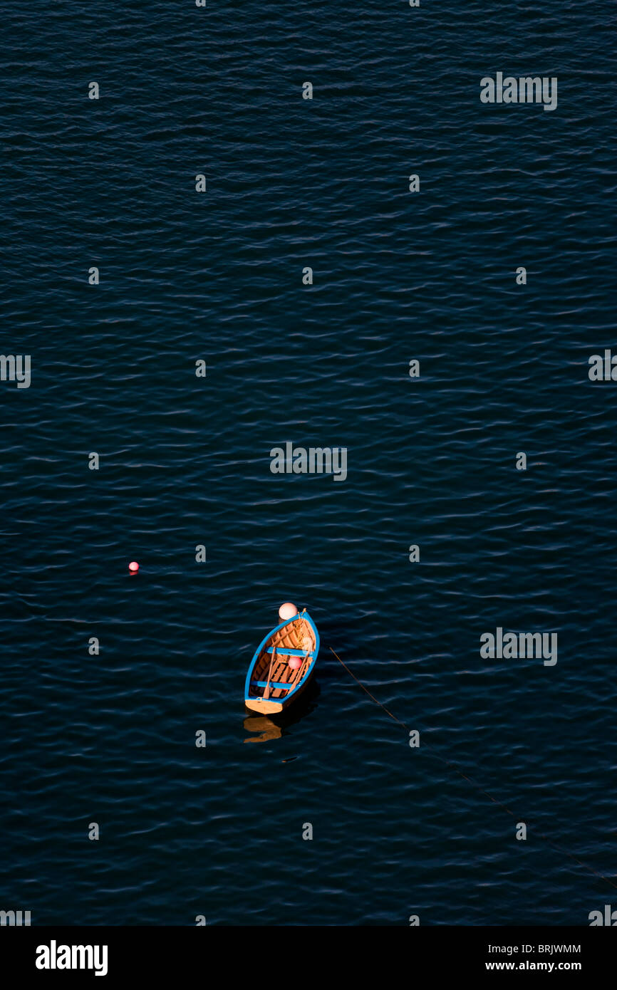 Lone riga in legno barca attaccata alla boa di ormeggio Foto Stock