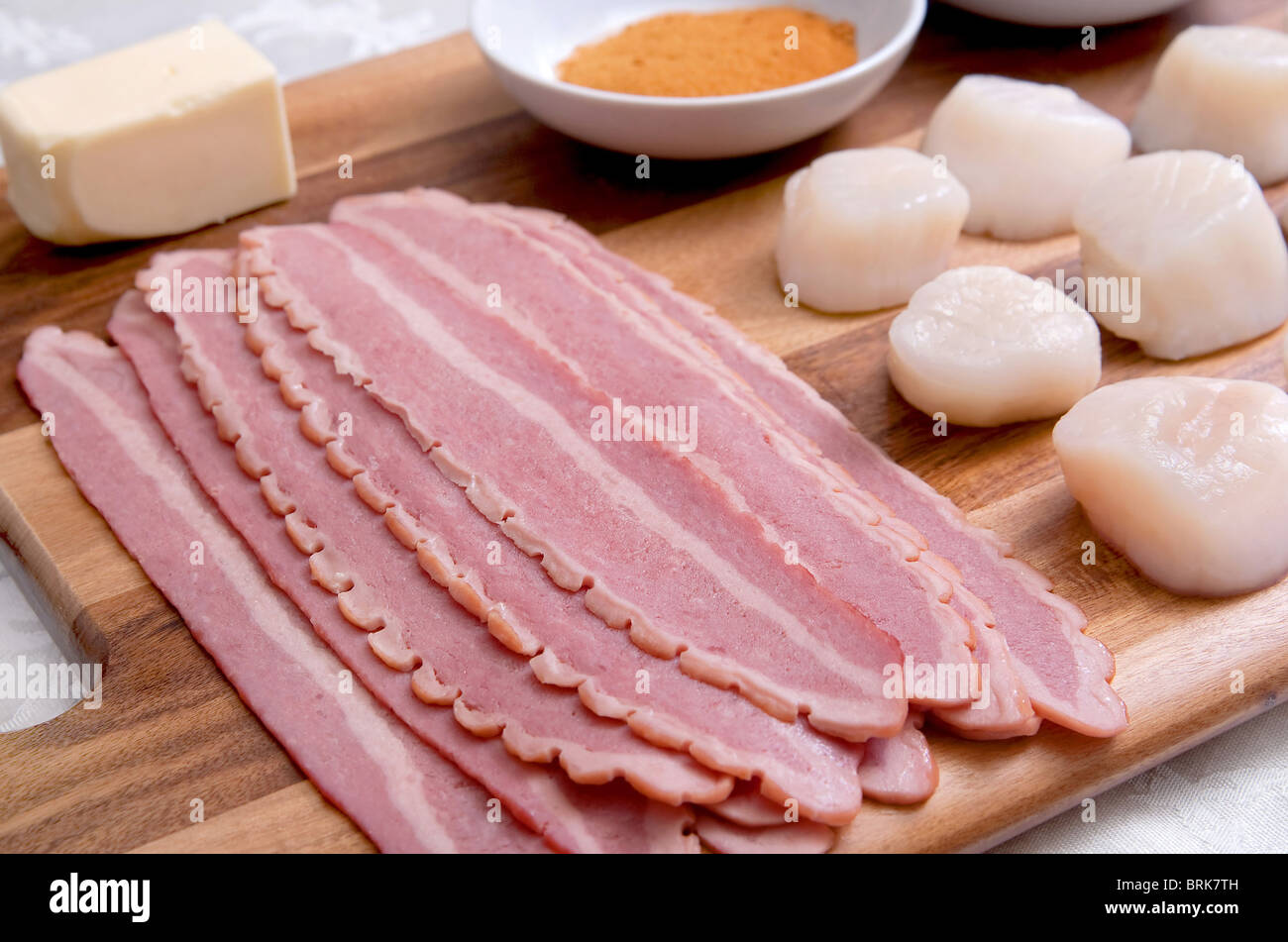 Mise en place su un tagliere di legno per un lotto di pancetta avvolto capesante prima di essere cucinati Foto Stock