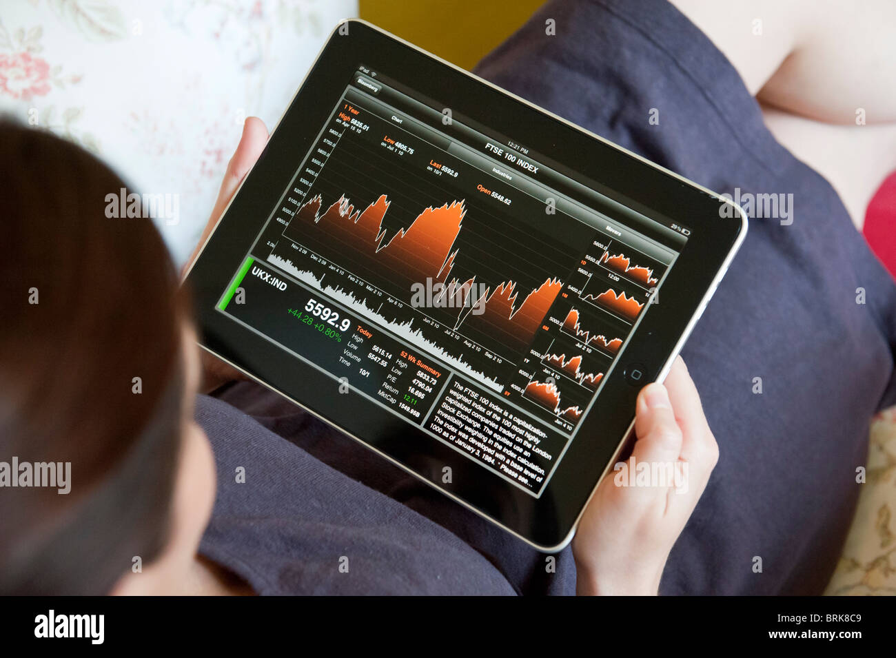 Donna controllo stock market performance usando un finance app su un computer tablet iPad Foto Stock