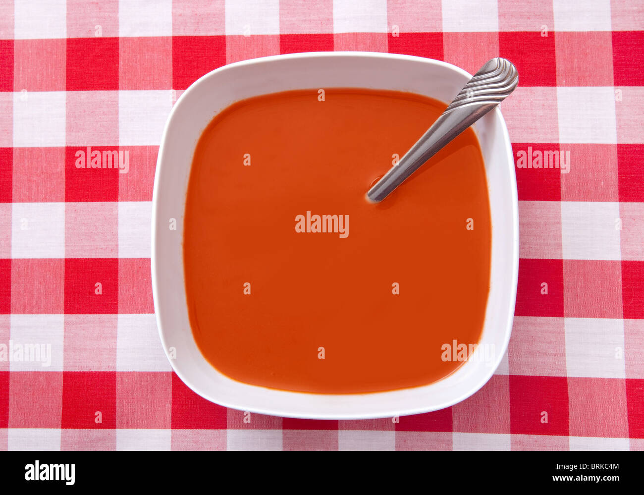 Una ciotola di zuppa di pomodoro contro un classico tradizionale rosso e bianco sfondo checker Foto Stock