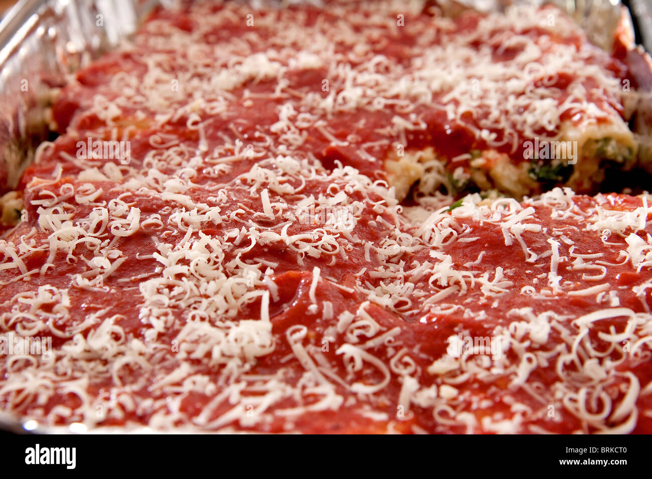 Vassoio pieno di manicotti di pasta conditi con formaggio pronto a cuocere in un tegame di stagno Foto Stock