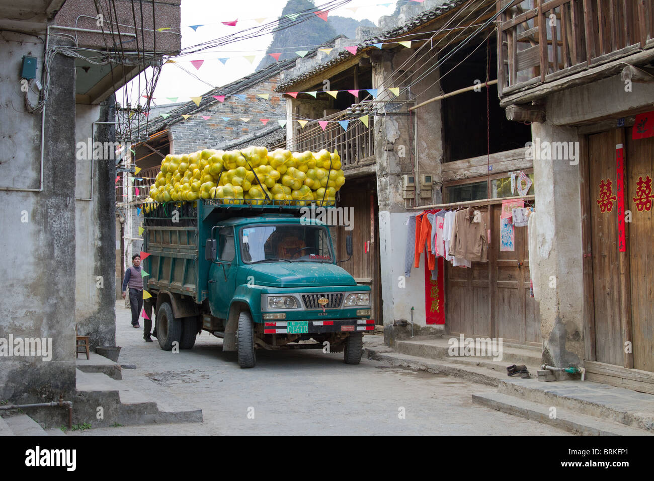 Carrello caricato con frutta negozia un piccolo vicolo in Cina Foto Stock