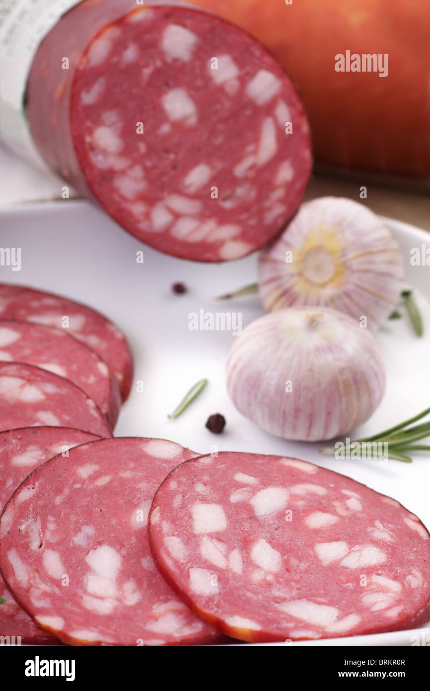 Affettare il salame accanto al rosmarino e aglio Foto Stock