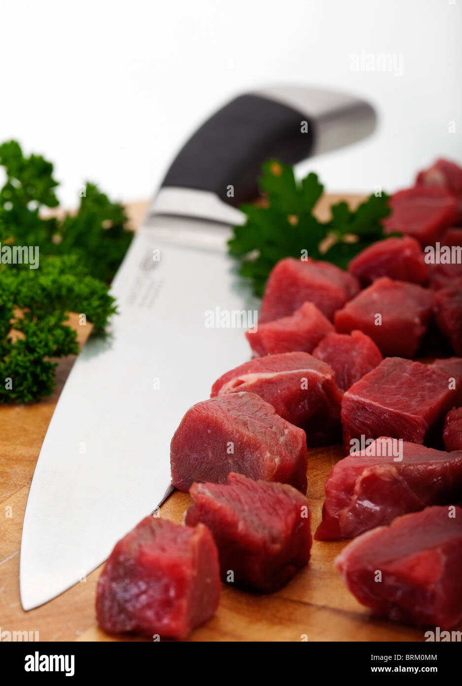 Un trito di stufare bistecca su un tagliere con coltello carving. Al di fuori della messa a fuoco lo sfondo Foto Stock