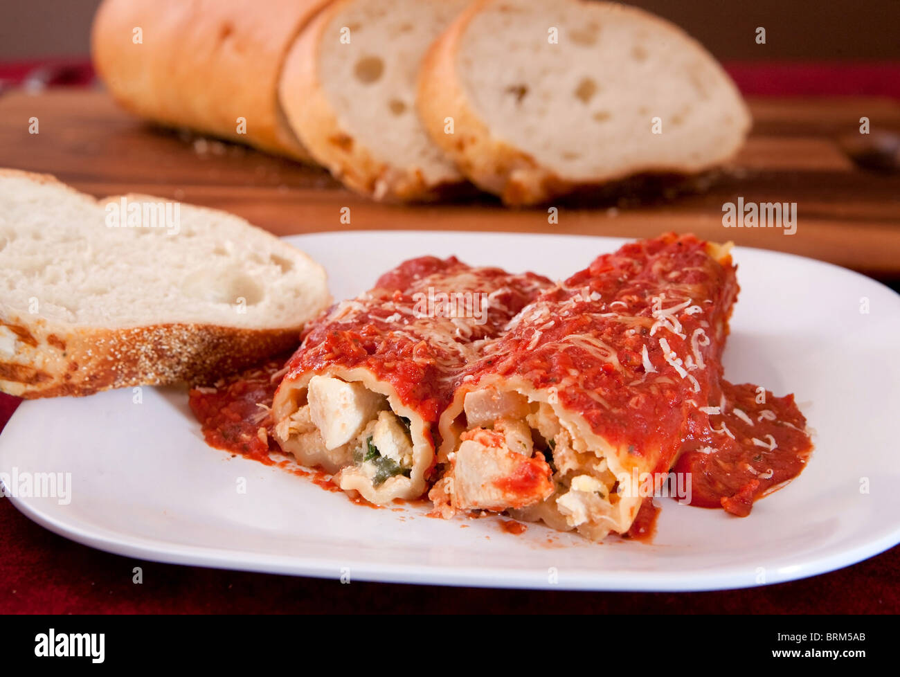 Due gustosi ripieni di gusci di manicotti condito con sugo per la pasta e pane italiano sul lato Foto Stock