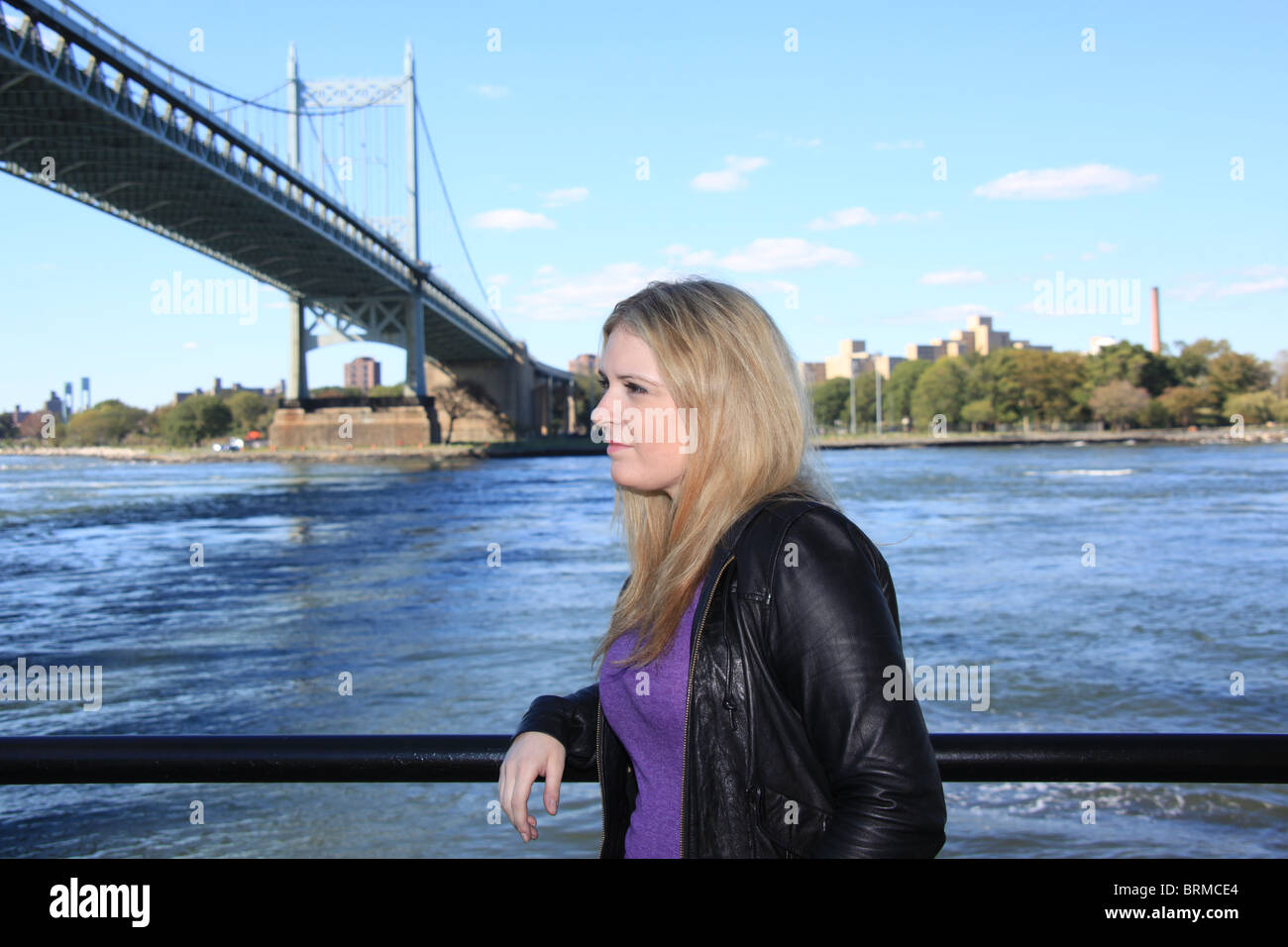 Attraente giovane donna bionda in piedi vicino a Triboro Bridge lungo la East River in New York City, 2 ottobre 2010 Foto Stock
