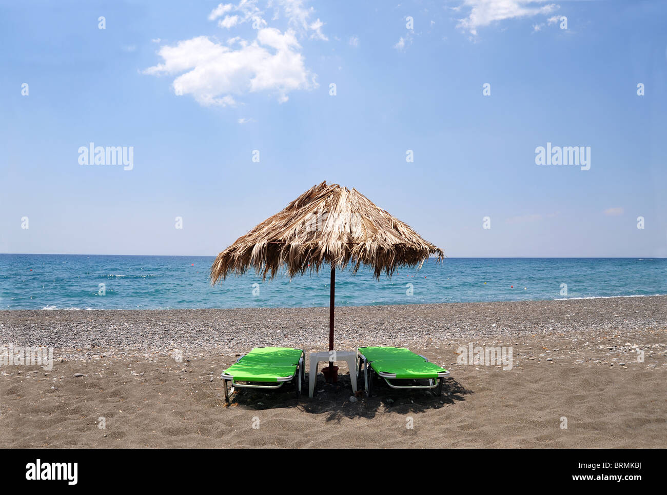Solo palm ombrellone sulla spiaggia con due sedie a sdraio. Immagine presa a Mirtos nel sud di Creta, Grecia Foto Stock