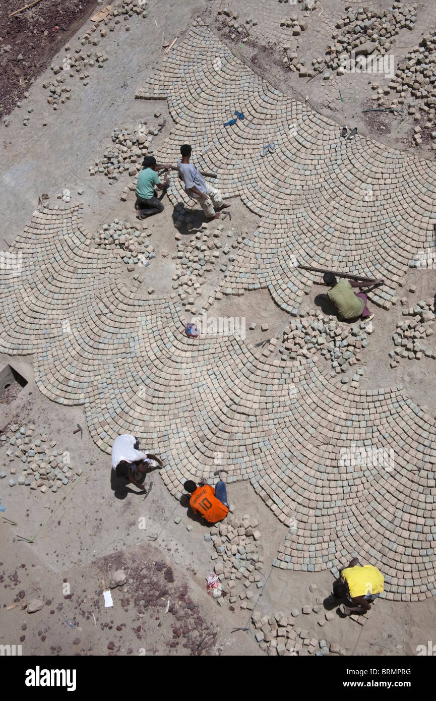 Vista aerea dei lavoratori che stabilisce una mattonella pavimentazione di pietra in una tecnica appresa durante il periodo coloniale da artigiani italiani Foto Stock