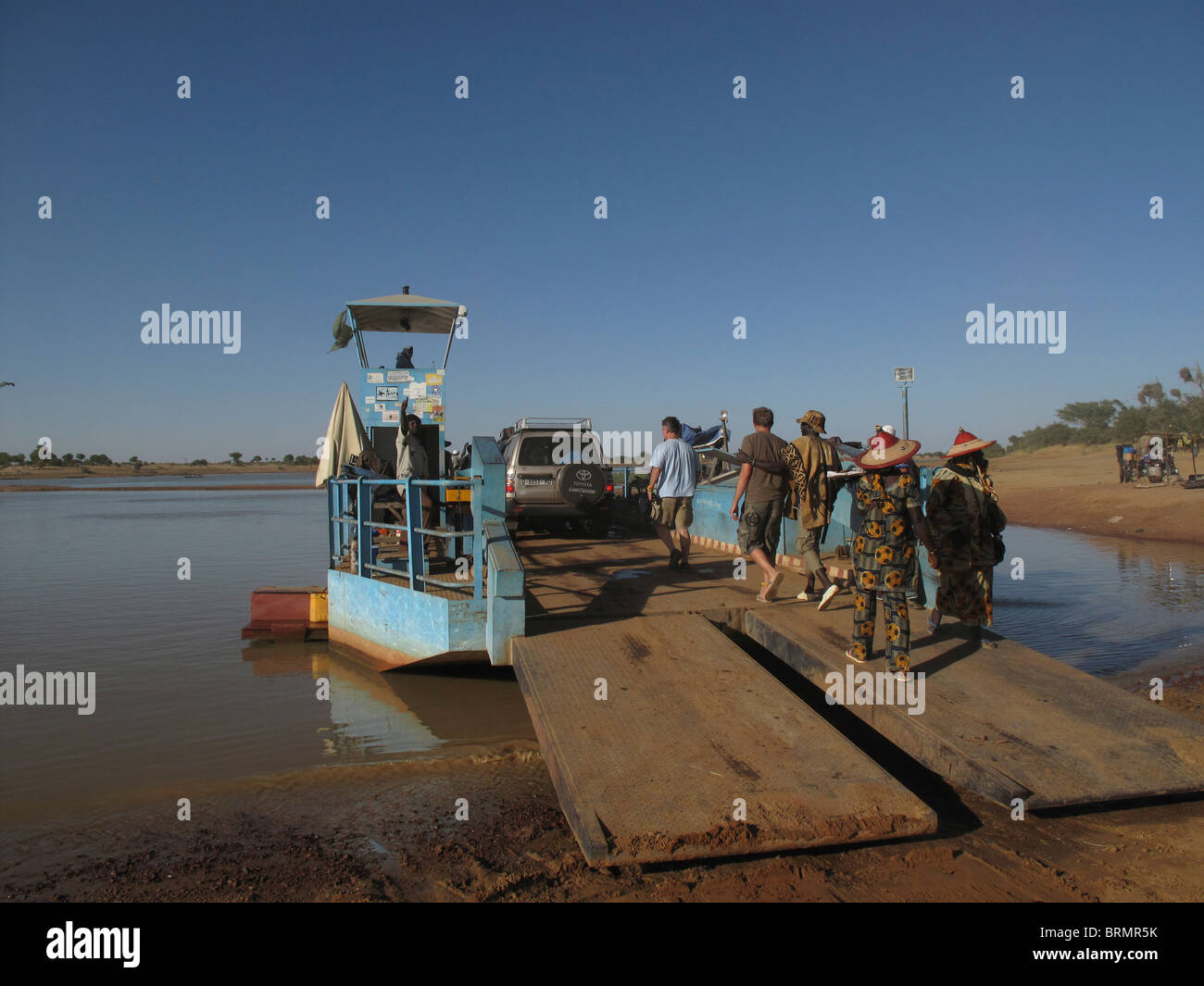 I turisti la preparazione di attraversare un fiume con le loro auto caricato su una nave traghetto Foto Stock