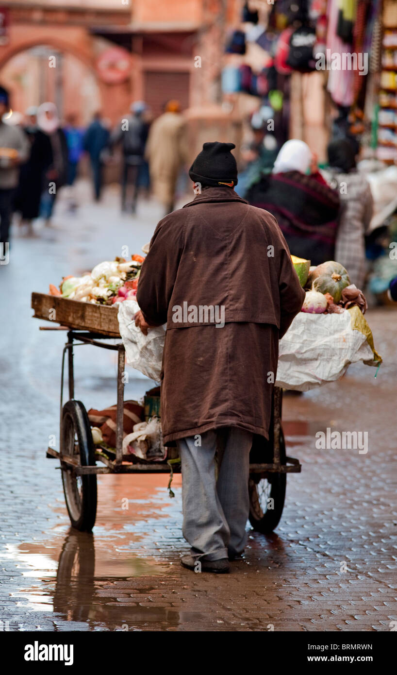 Un riff uomo spingendo un carrello pieno di verdura fresca per la piazza del mercato Foto Stock