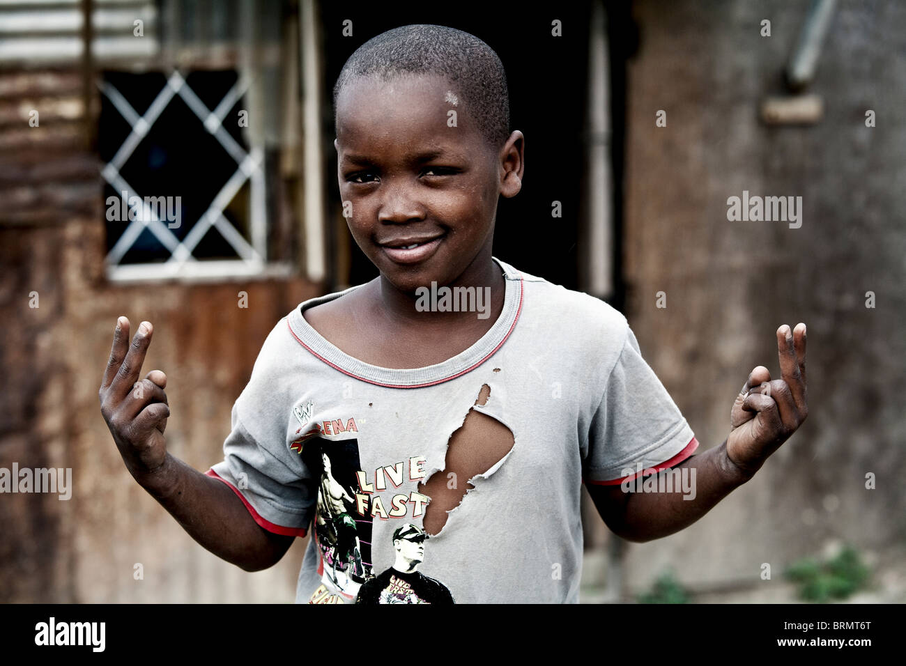 Ritratto di un giovane township ragazzo che indossa un strappata T-shirt Foto Stock