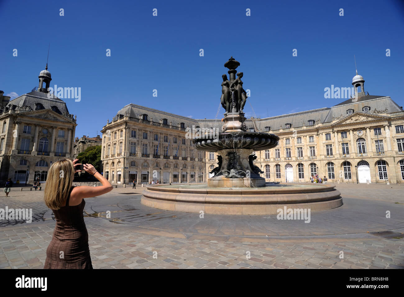 Francia, Bordeaux, Place de la Bourse, turista che scatta una foto alla fontana delle tre Grazie Foto Stock