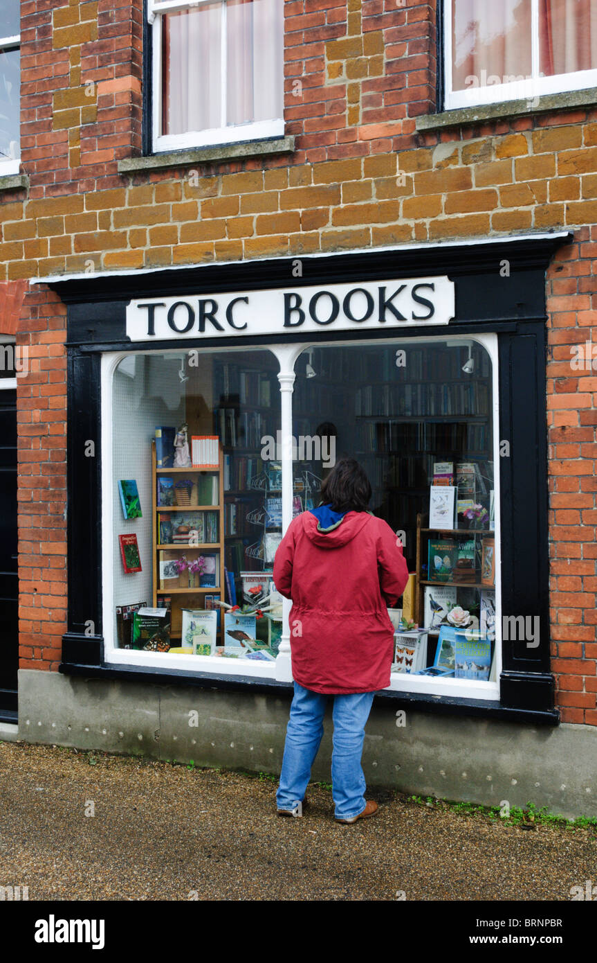 Una donna che guarda nella finestra di Torc libri, una piccola libreria di seconda mano nel villaggio di Snettisham, Norfolk Foto Stock