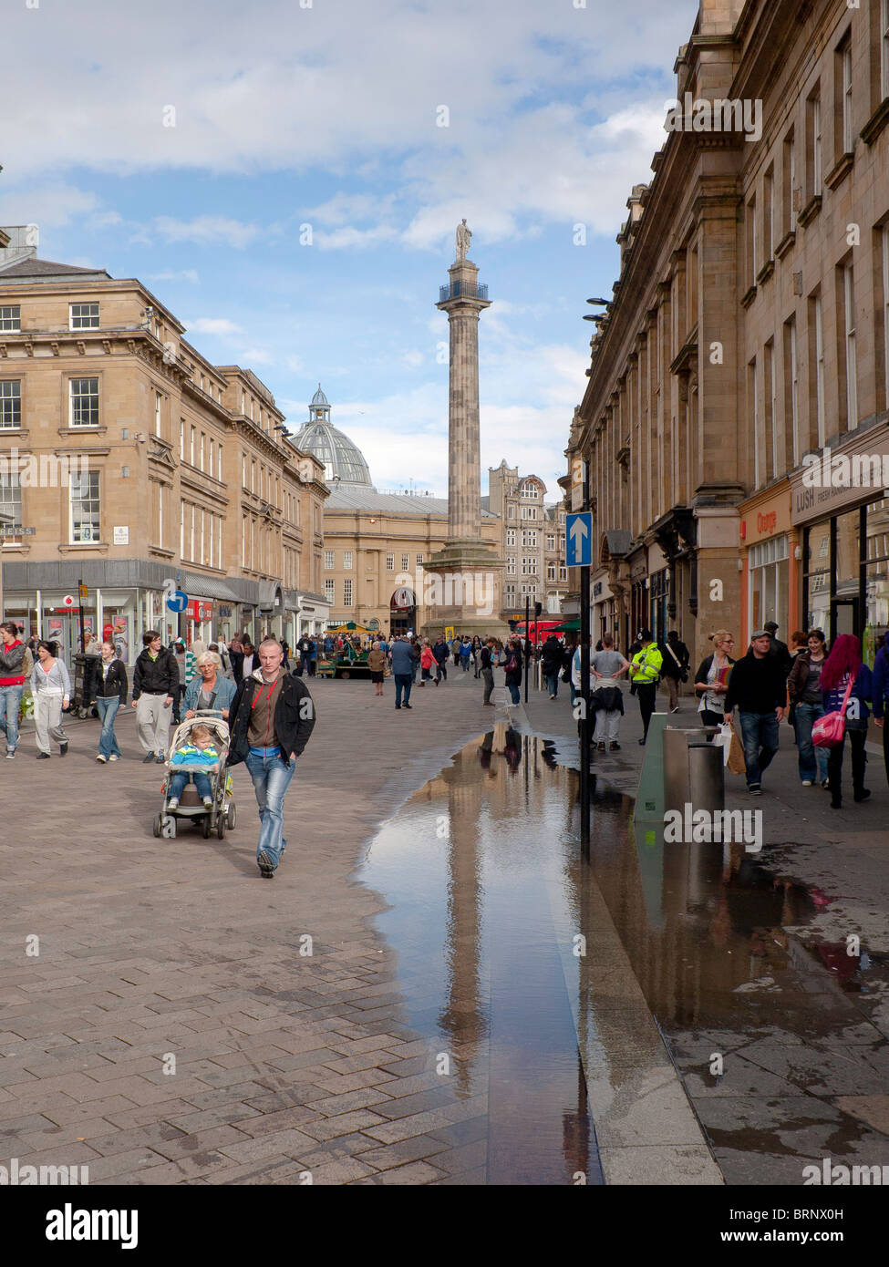 Grainger Street Newcastle upon Tyne con Lord Grey's Monument riflessa in una pozza Foto Stock