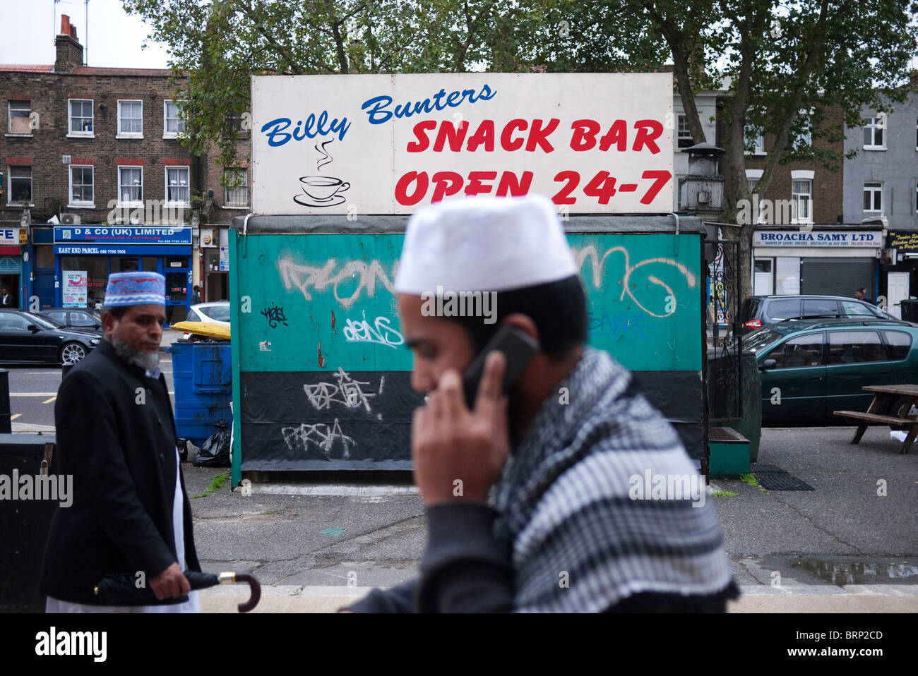 I musulmani in Whitechapel passare una chiusa snack bar. Uno su un telefono cellulare. Foto Stock