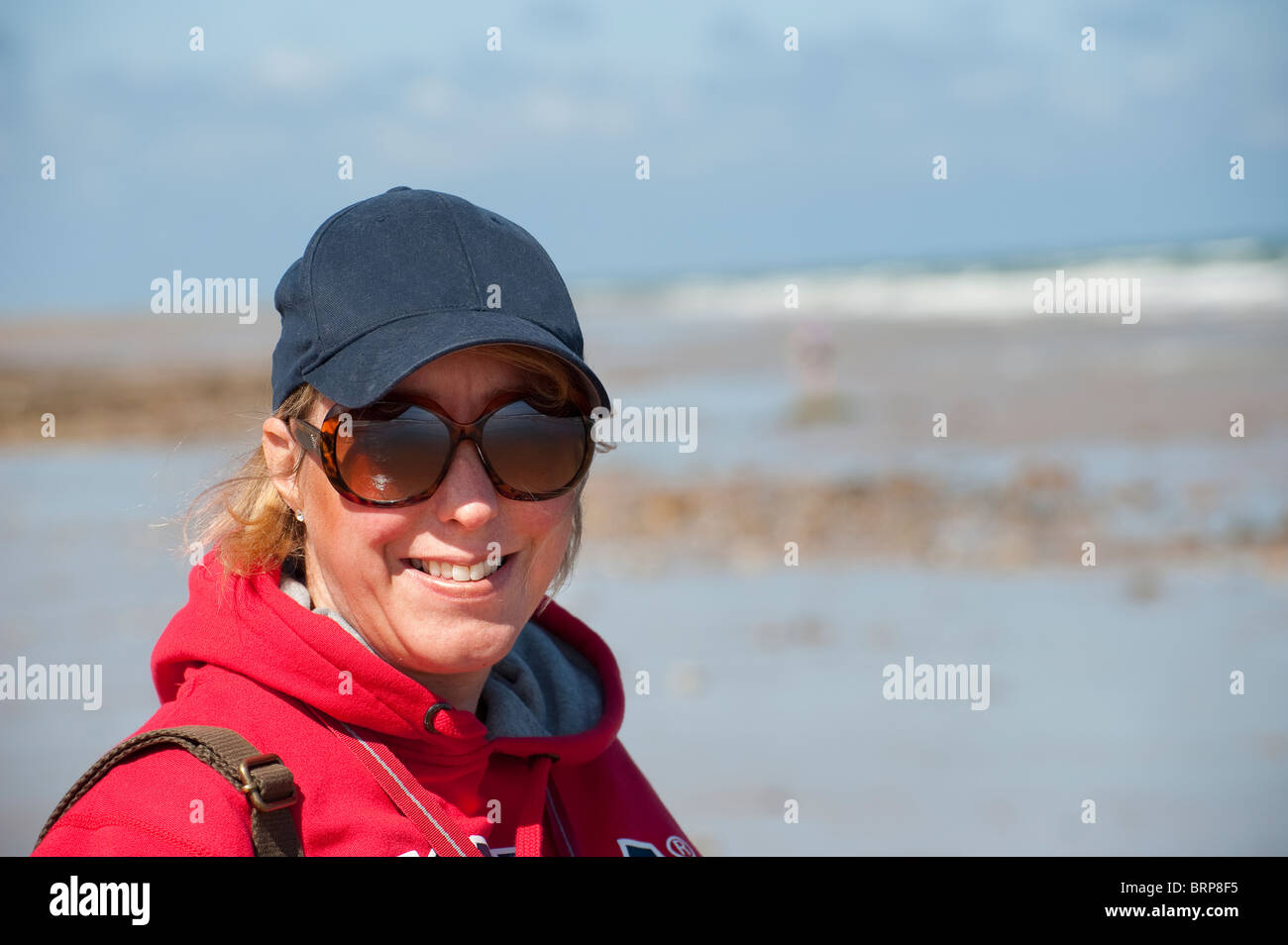 Outdoor ritratto di una donna sorridente, godendo di una giornata al mare in Inghilterra. Foto Stock
