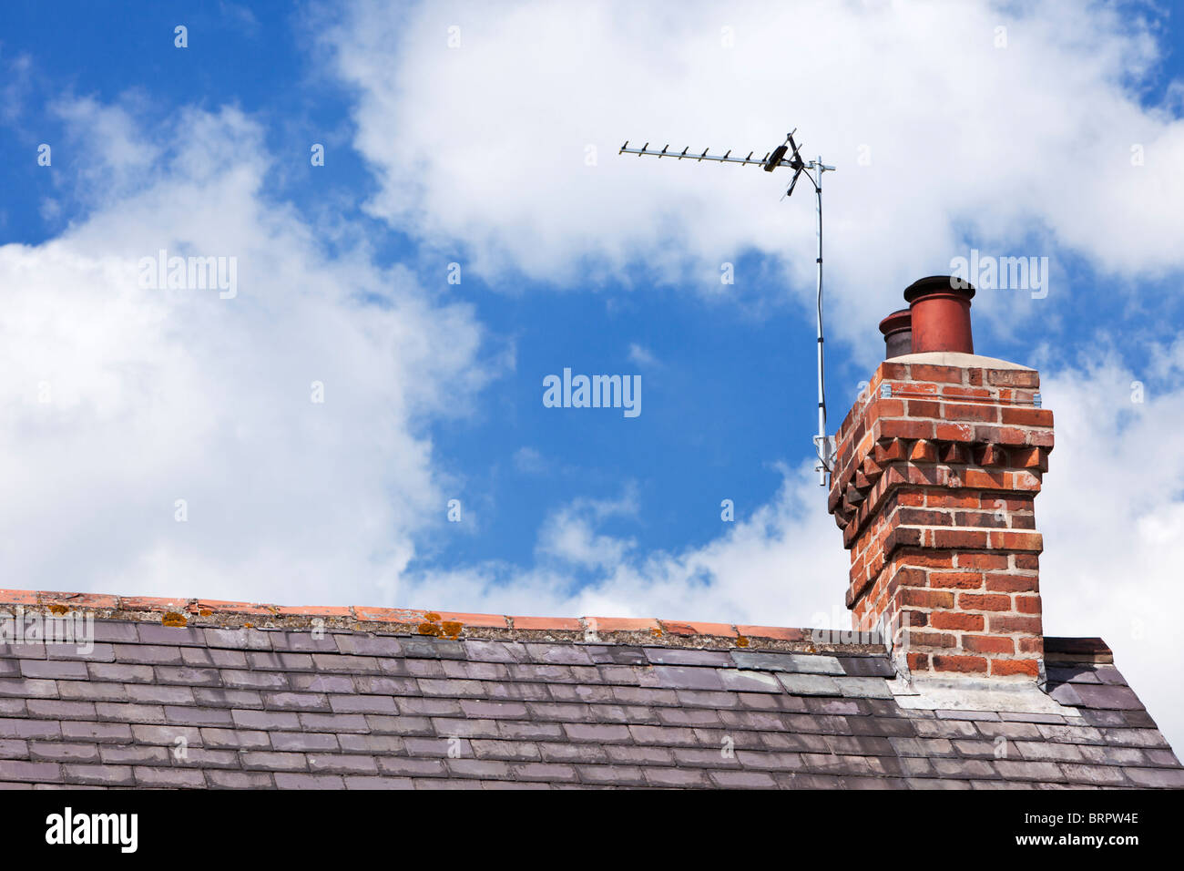 Antenna TV su una casa tetto in ardesia con mattoni rossi camino REGNO UNITO Foto Stock