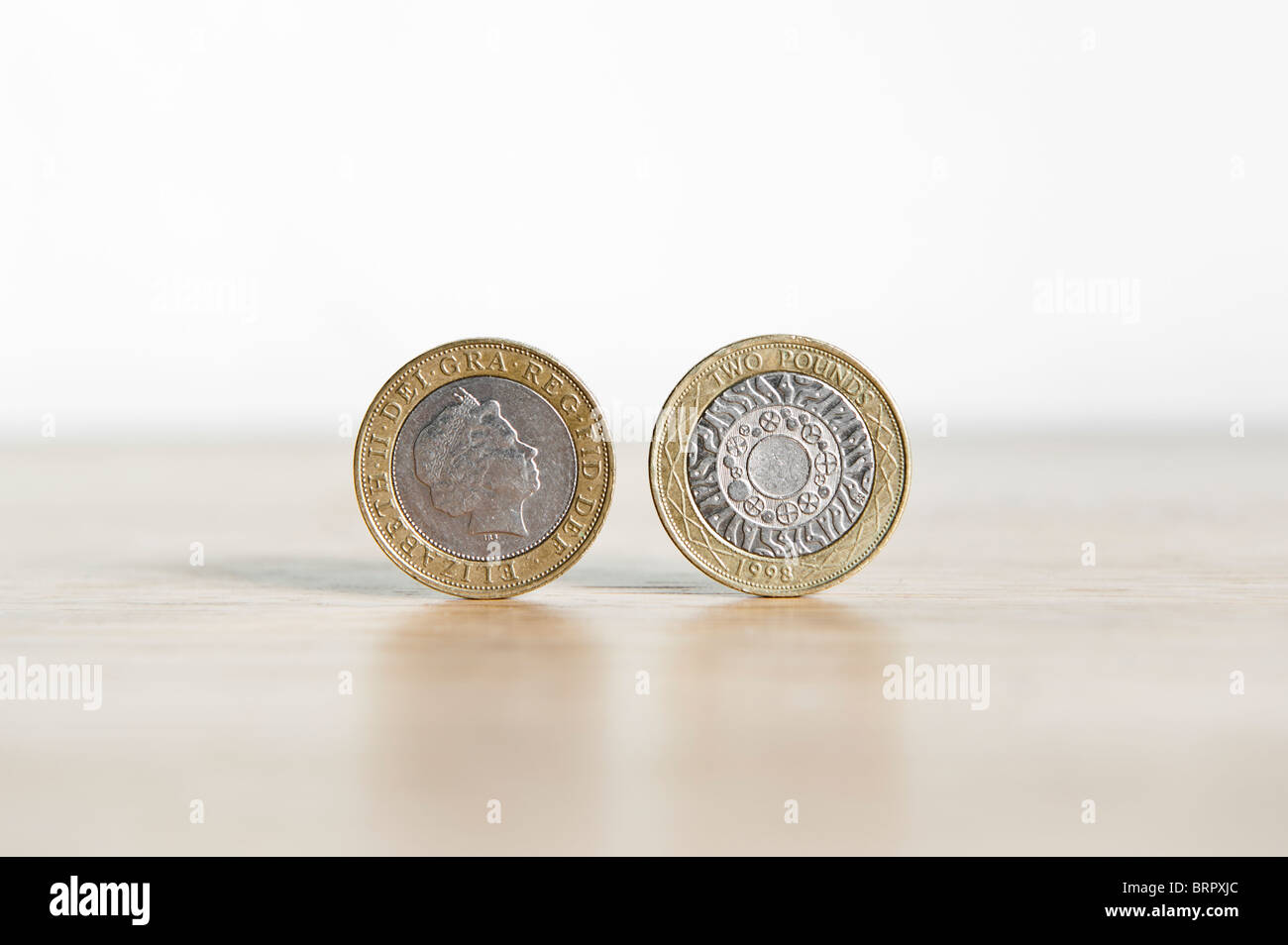 Due Pound coin isolato, in piedi sul bordo con ombra Foto Stock
