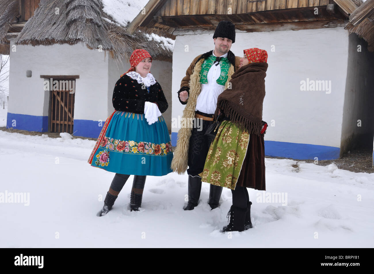 Uomini e donne in costumi folk hanno una chat in inverno sul tempo di Natale Foto Stock