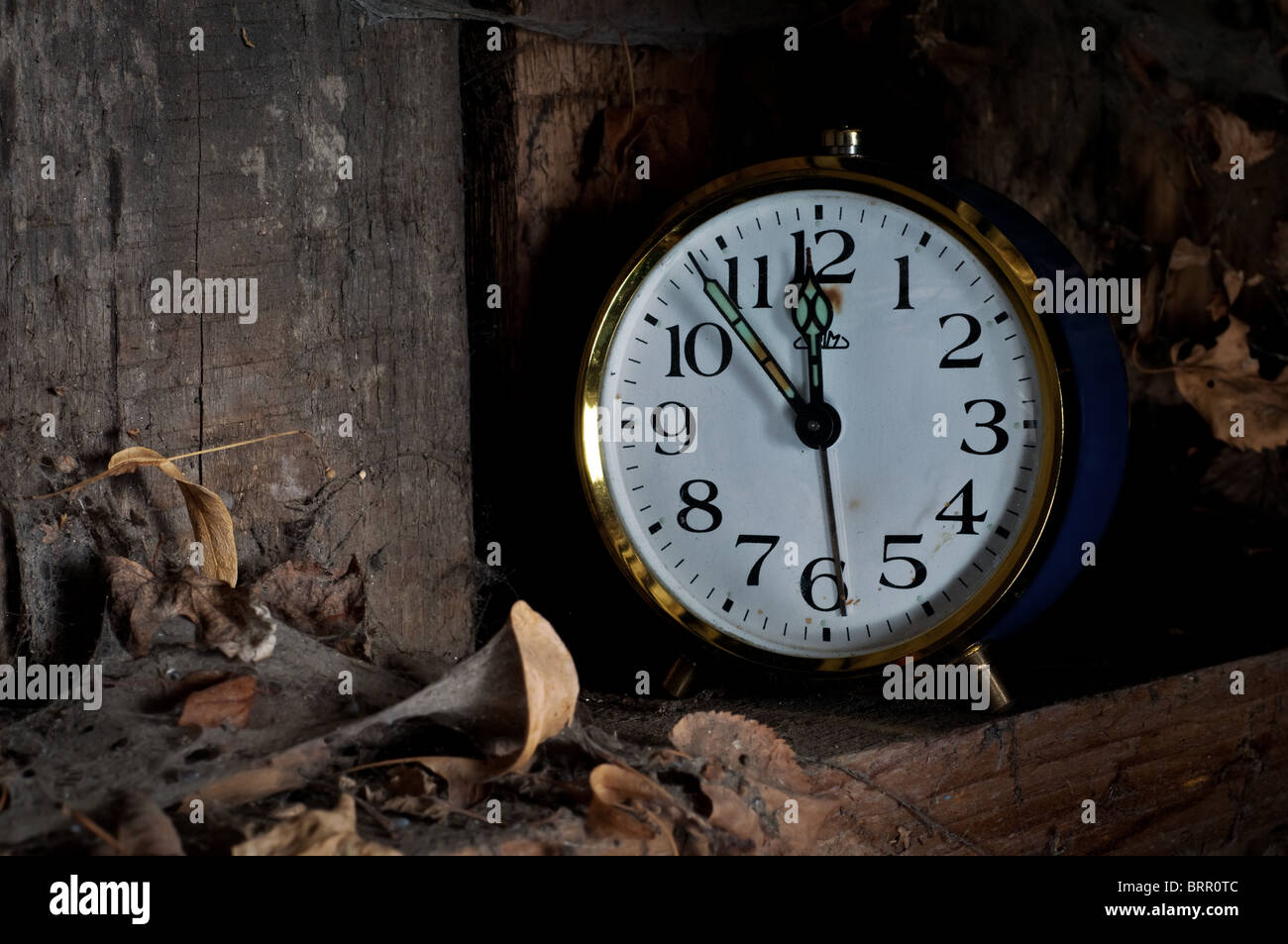 In passato il concetto di tempo - vecchio orologio sveglia dimenticato su uno scaffale con foglie e ragnatele. Foto Stock