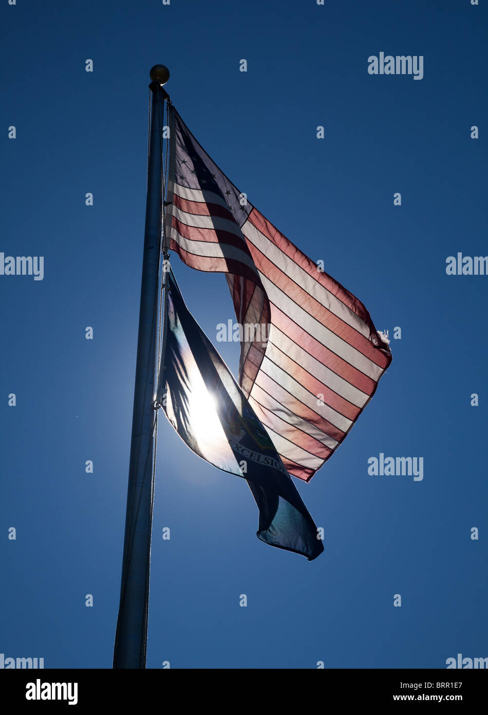 Stelle e strisce illuminate da dietro e il New York State flag su un pennone Foto Stock