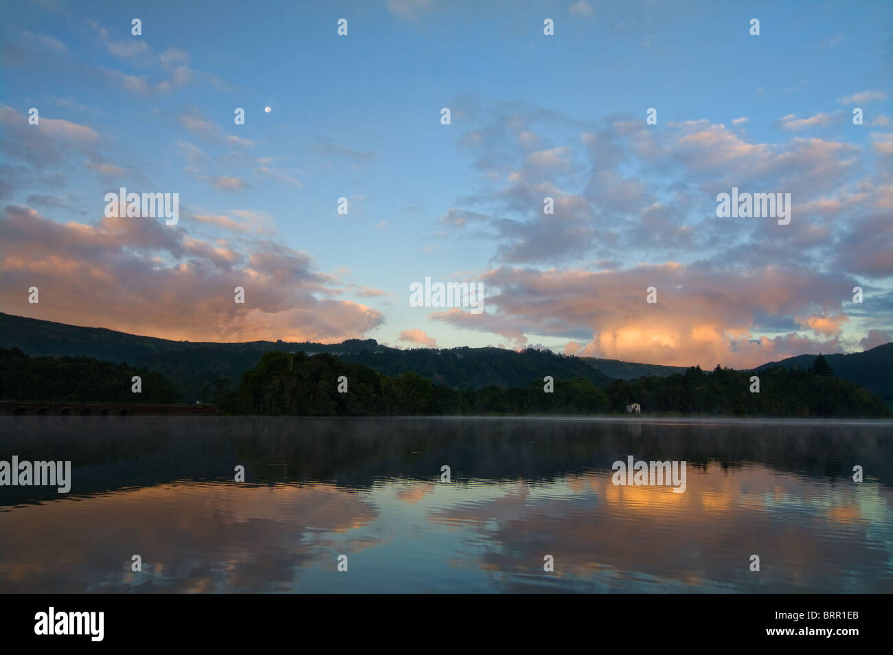 Paesaggio a specchio del lago Sete Cidades all'alba con la luna ancora visibile nel cielo, preso dalla valle delle "sette città" nelle Azzorre. Foto Stock