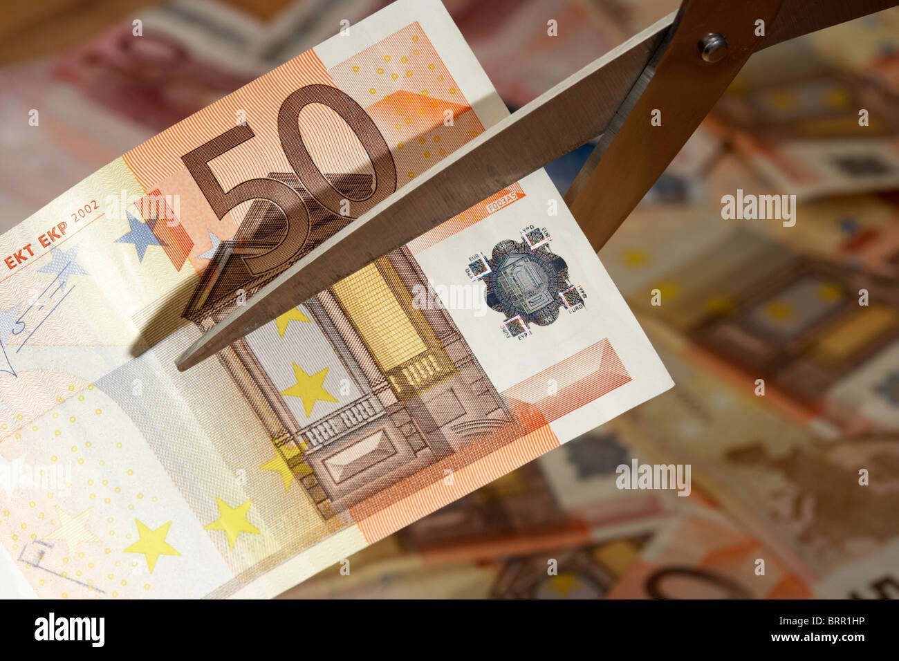 Pila di cinquanta banconote in euro con 50 euro nota essendo tagliato con un paio di forbici in Europa eurozona Foto Stock