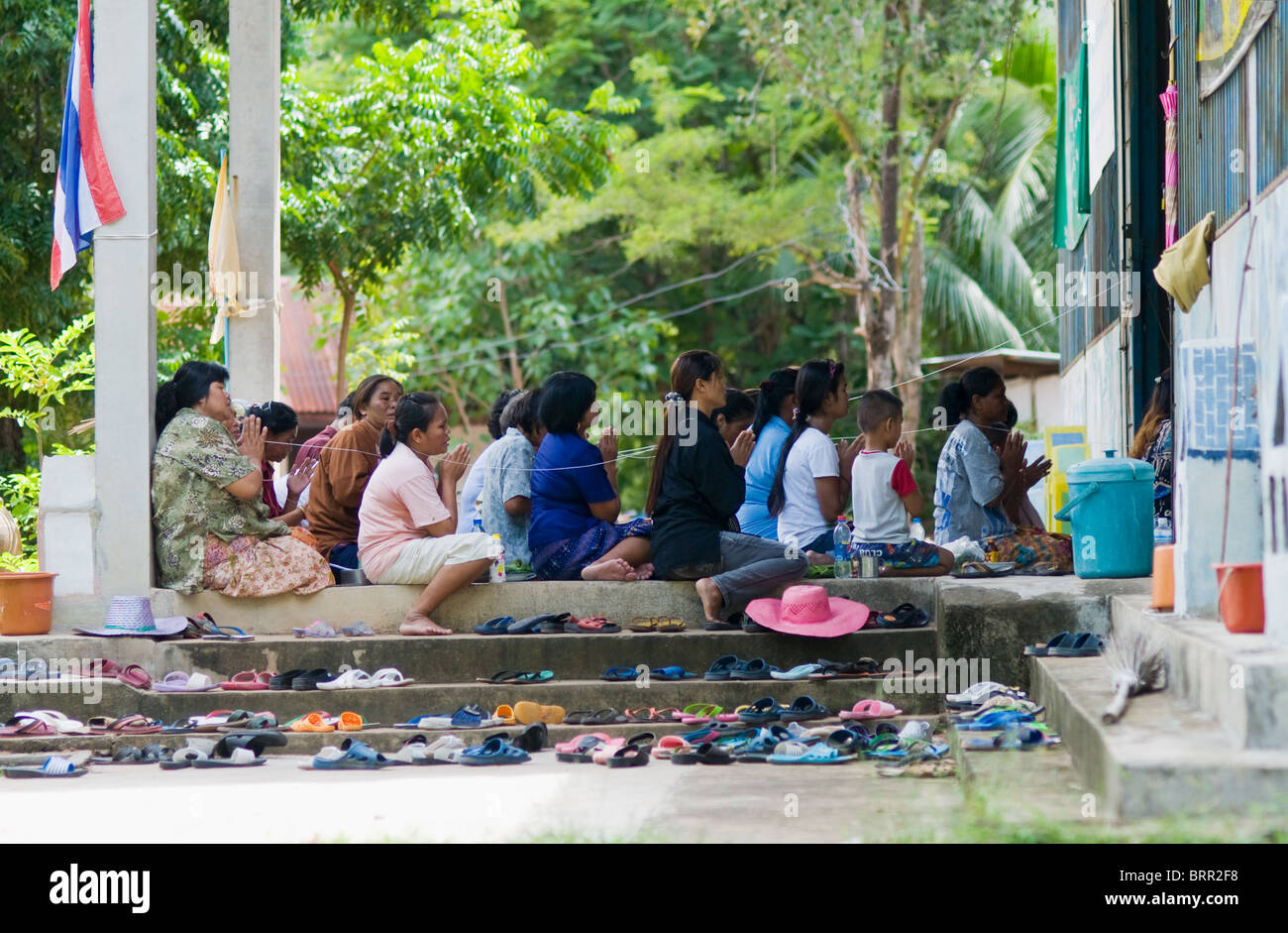 Gli abitanti di un villaggio di pregare in un tempio in Thailandia rurale Foto Stock