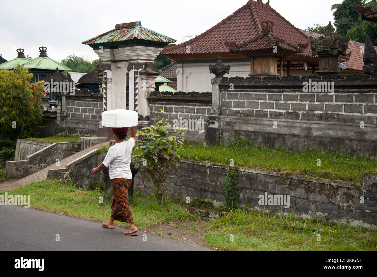 Donna indonesiana di Bali portando acqua sulla sua testa Foto Stock