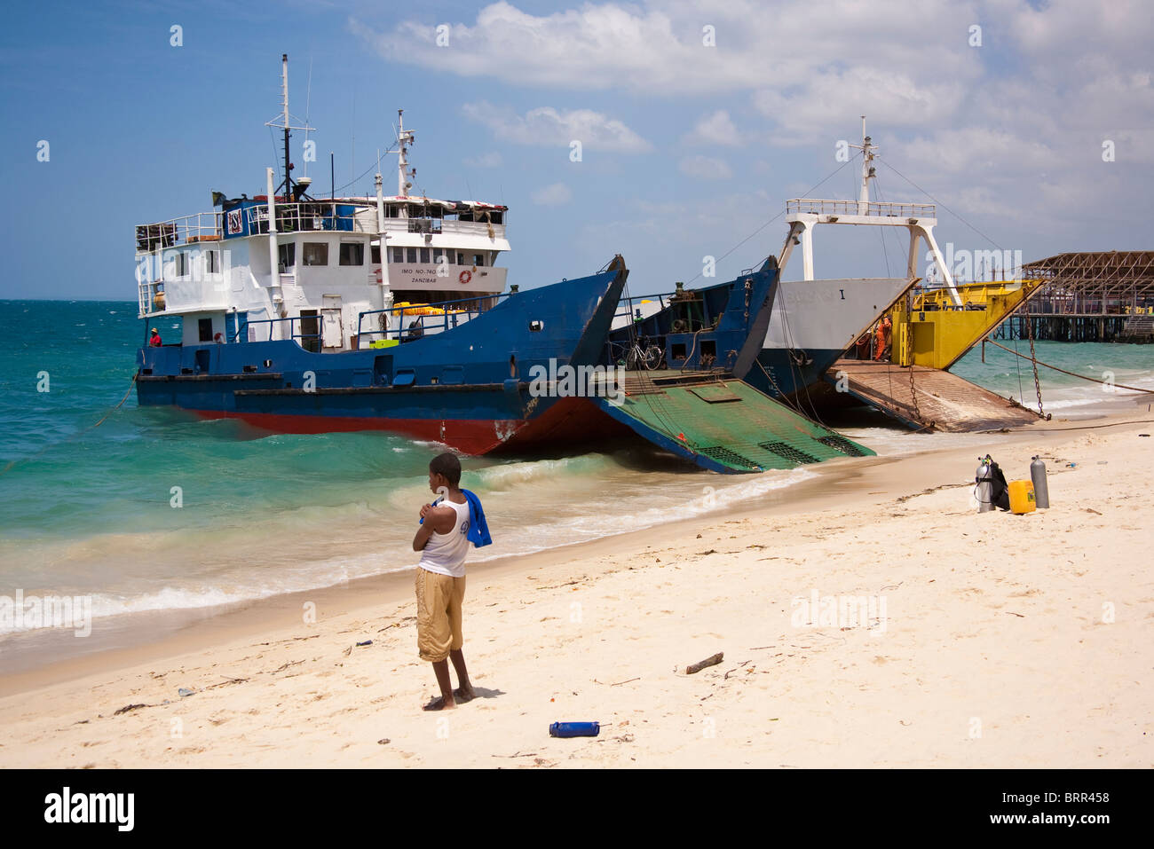 Uomo locali sulla spiaggia con due imbarcazioni commerciali con rampe di carico Foto Stock