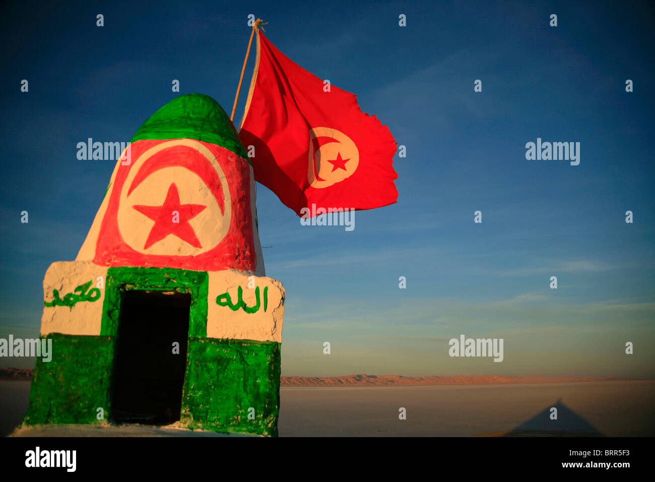 Bandiera tunisina vola su un piccolo monumento accanto al lago salato di Chott el-Jerrid Foto Stock