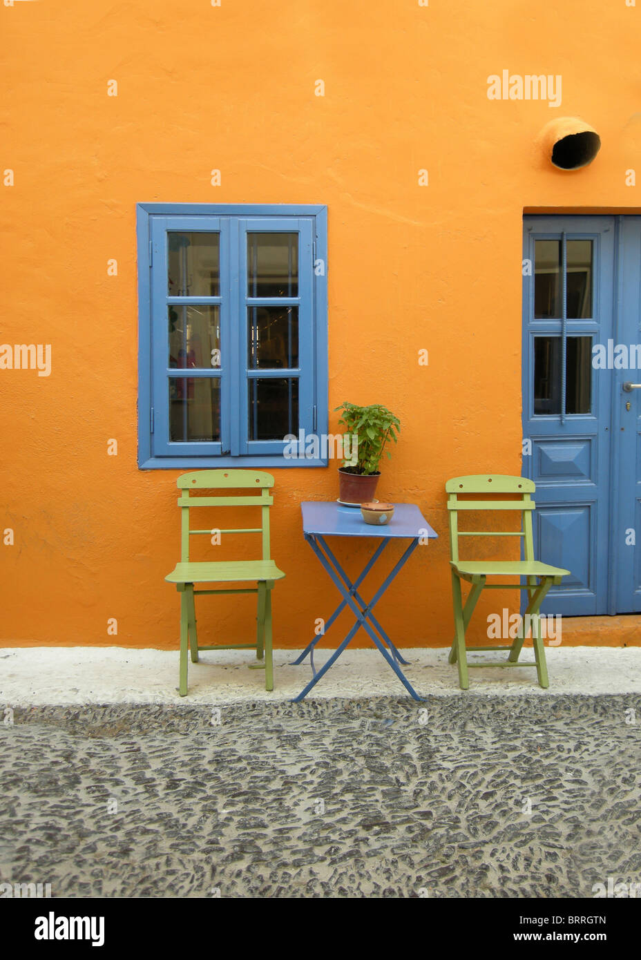 Sedie e un tavolo al di fuori di una coloratissima casa anteriore sull'isola greca di Santorini Foto Stock