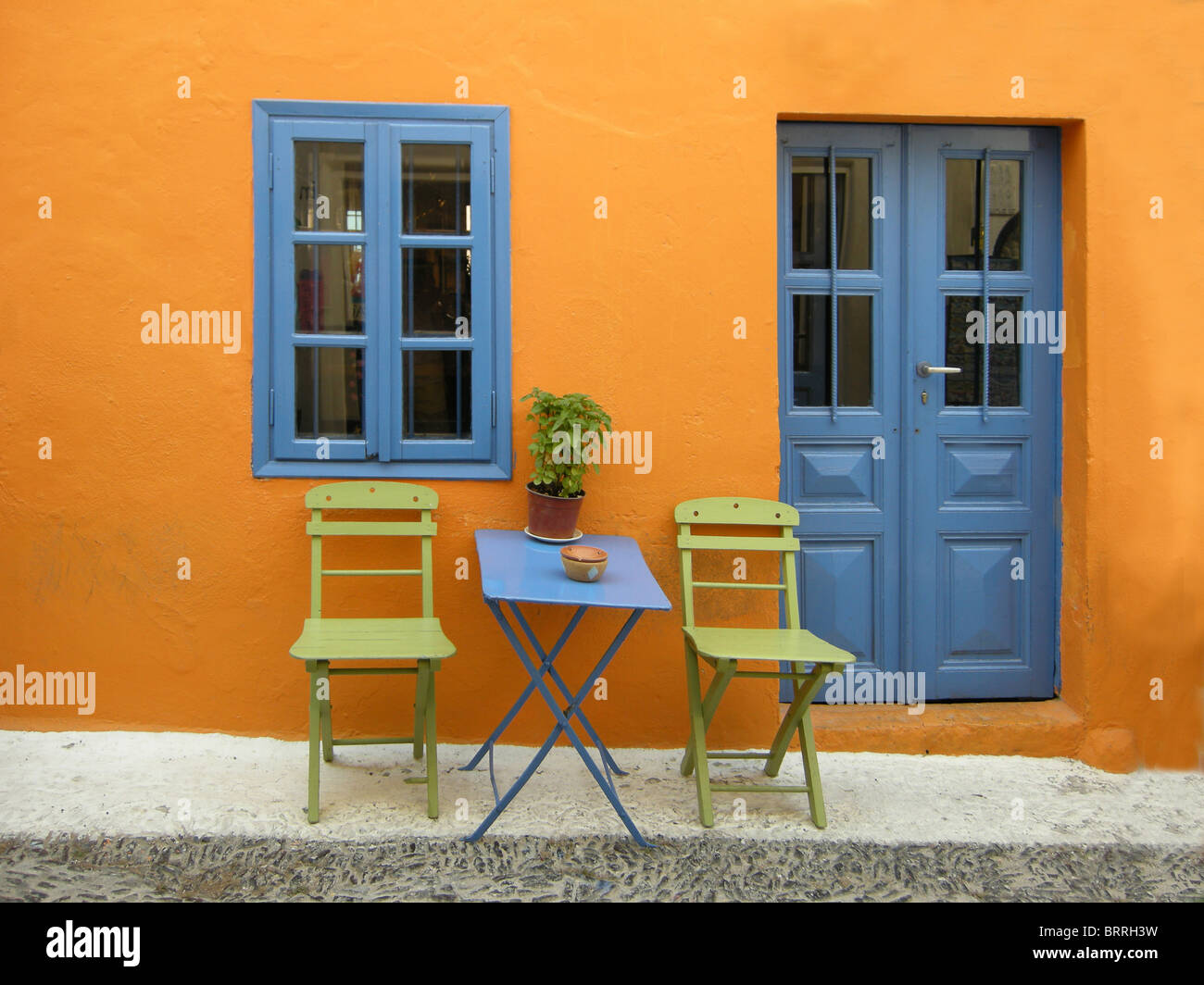 Sedie e un tavolo al di fuori di una coloratissima casa anteriore sull'isola greca di Santorini Foto Stock