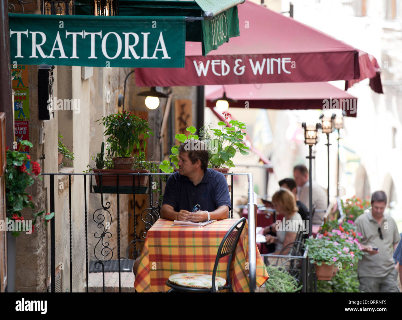 Un cliente seduto a un tavolo al di fuori di un ristorante in attesa per il suo pasto in San Gimignano Toscana Italia Foto Stock