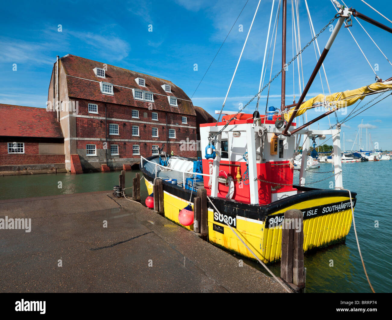 Giallo commerciale shell peschereccio ormeggiata lungo banchina Ashlett su Southampton acqua con mulino vecchio edificio di mattoni rossi Foto Stock