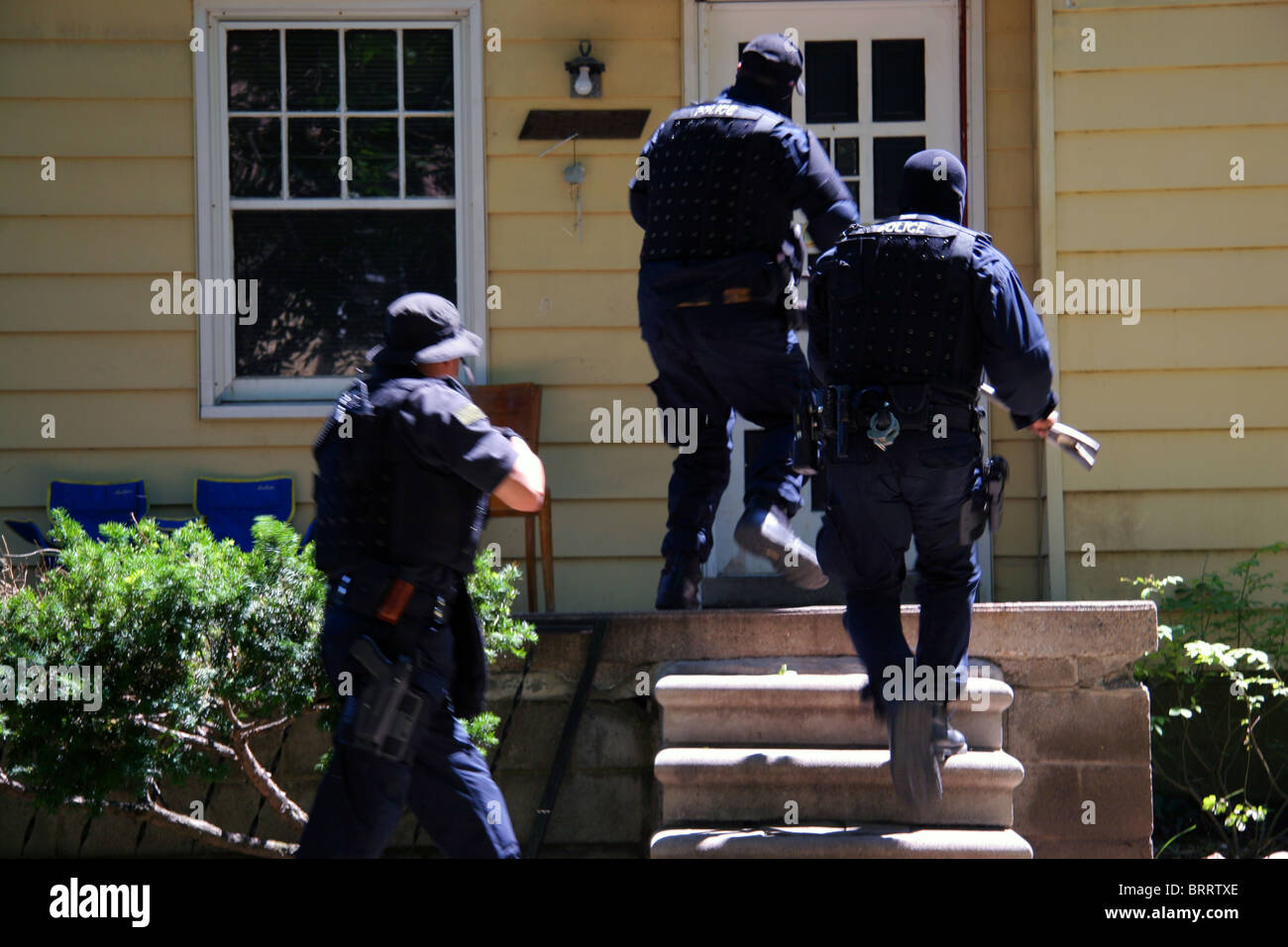 Funzionario di polizia dalla polizia di Detroit unità narcotici corrono verso una casa durante una droga raid. Foto Stock