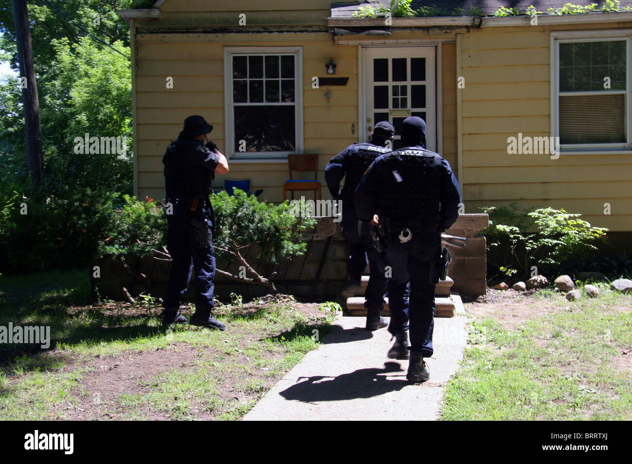 Funzionario di polizia dalla polizia di Detroit unità narcotici approccio una casa durante una droga raid. Foto Stock
