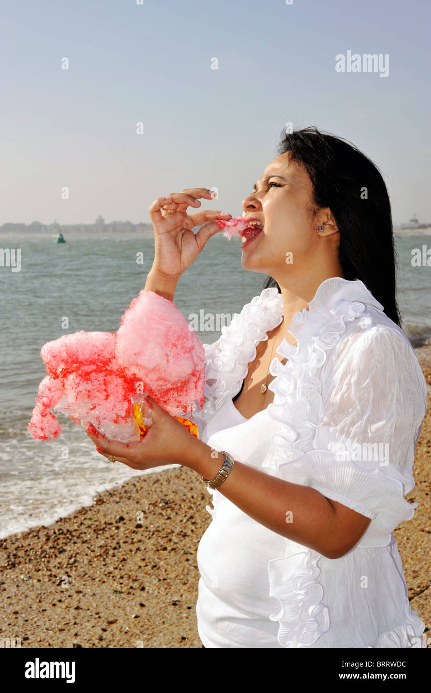 giovane donna che mangia filo di caramella sulla spiaggia southsea inghilterra regno unito Foto Stock