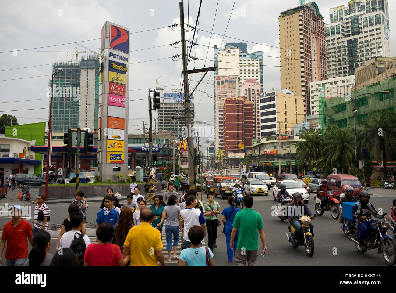 I pedoni attraversano in corrispondenza di un incrocio occupato in Makati City Metro Manila, Filippine. Foto Stock