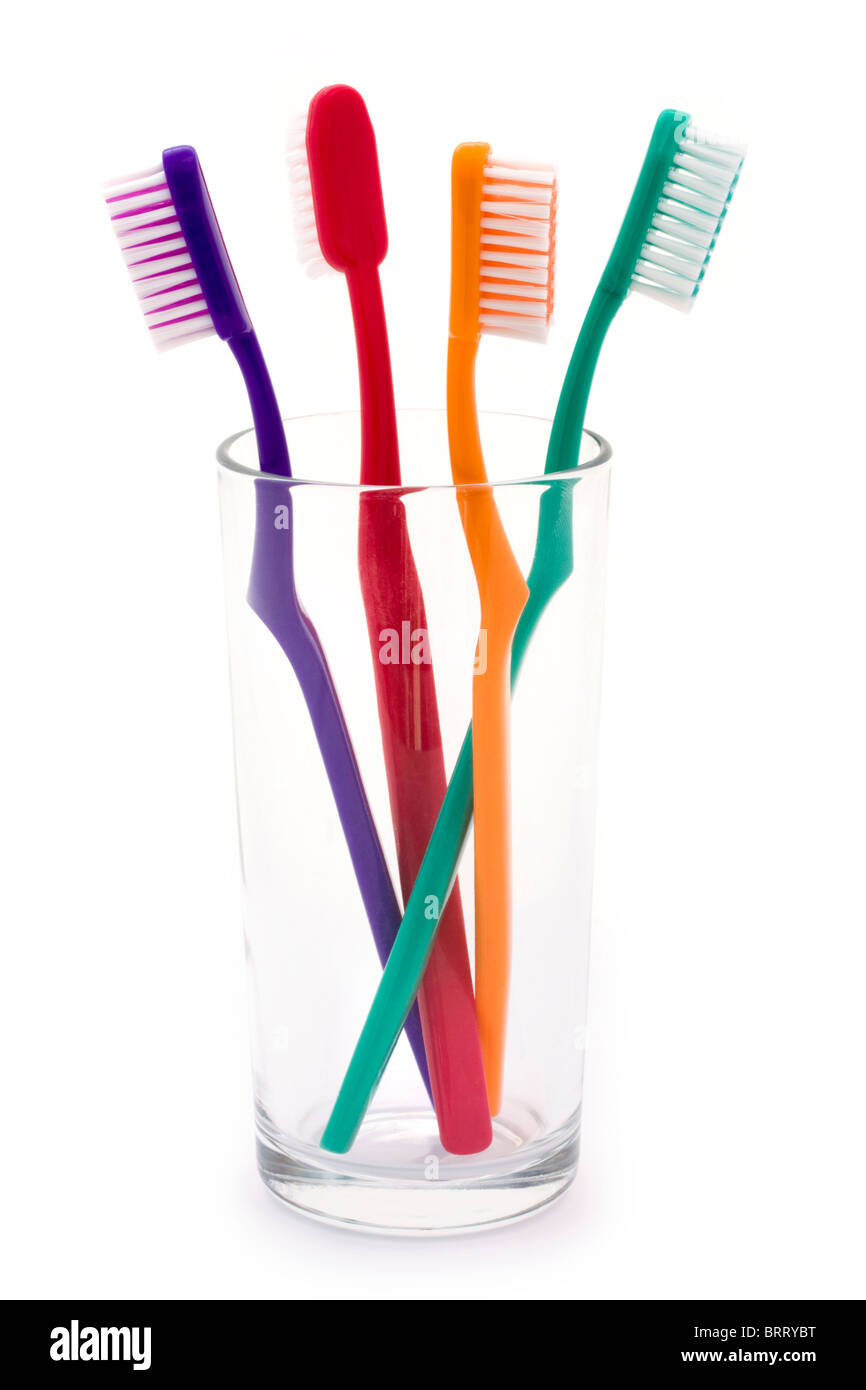 Gli spazzolini da denti colorati in un vetro su bianco Foto Stock
