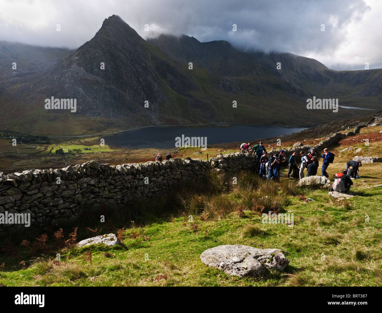 Snowdonia: Tryfan e il Glyders salire oltre Llyn Ogwen, mentre un gruppo di escursionisti che poggiano sui fianchi della penna yr Wen Ole Foto Stock
