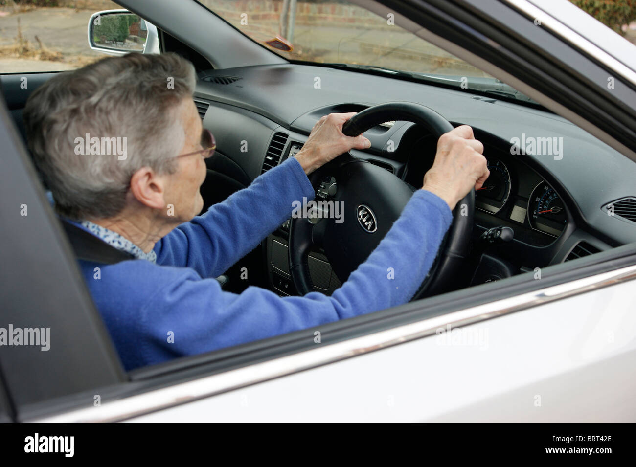 Donna anziana conducente al volante di una vettura con attenzione la guida Foto Stock