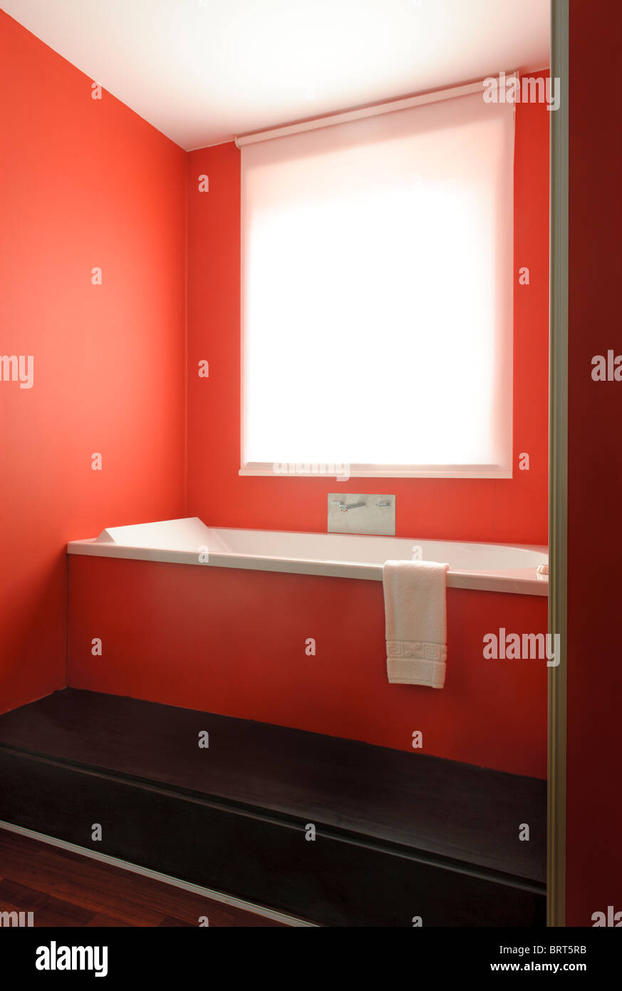 Progettate in stile contemporaneo bagno arancione con una luminosa finestra sopra la vasca da bagno Foto Stock