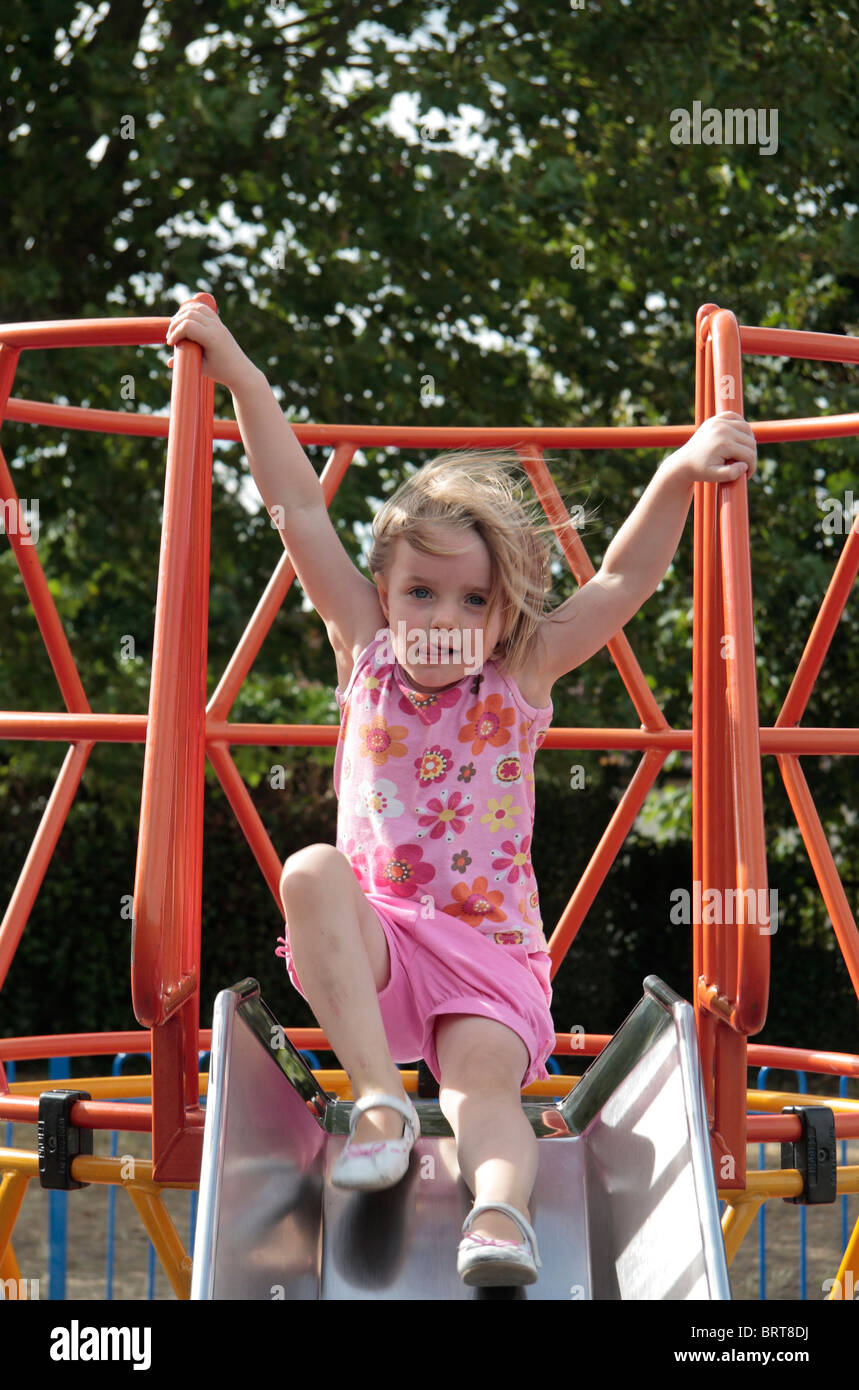 Un giovane bambino gioca su una diapositiva in un parco giochi all'aperto. Foto Stock