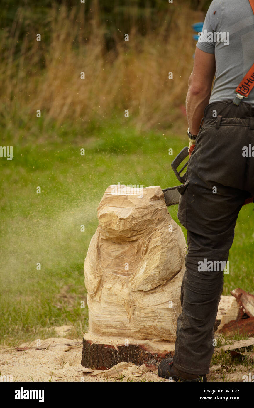 Artigiano del legno carving un orso statua utilizzando una motosega. Nota: grani di segatura sono battenti in tutto la foto! Foto Stock