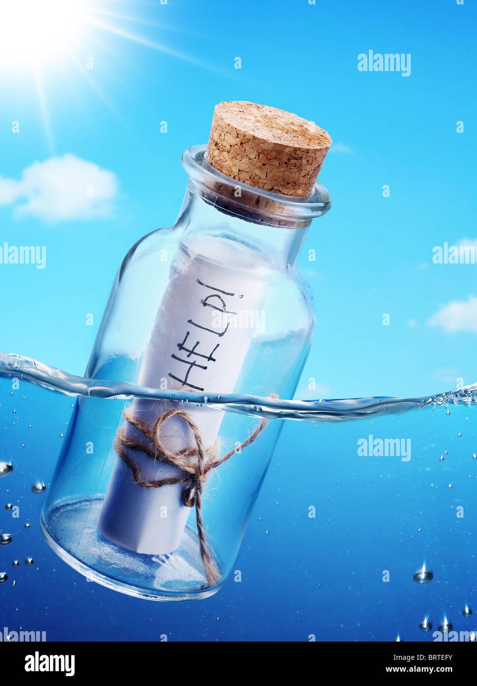Bottiglia con messaggio di aiuto fluttuante nel vedere le onde. Foto Stock