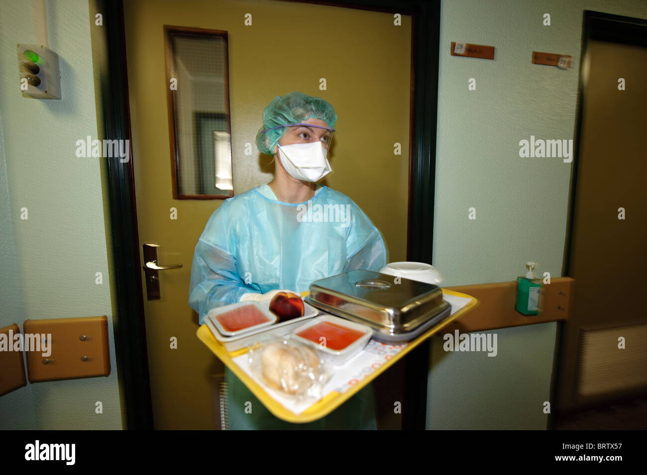 L'operatore sanitario con maschera protettiva trasporta un vassoio con i pasti per i pazienti in un ospedale - coronavirus corona virus Foto Stock L'operatore sanitario con maschera protettiva trasporta un vassoio con i pasti per i pazienti in un ospedale - coronavirus corona virus Foto Stock