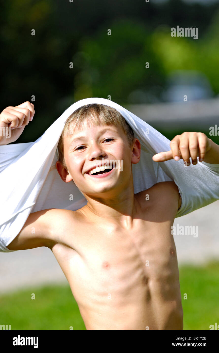 Ragazzo sorridente di spogliare la camicia Foto Stock